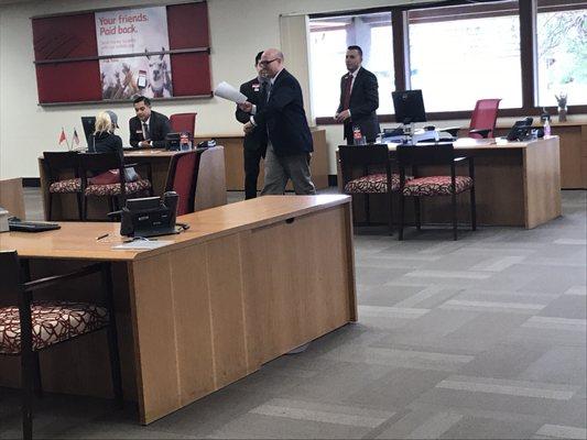 Five guys in suits doing nothing and only two people behind the counter.