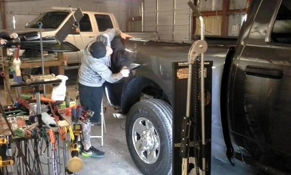 He is using a special hammer to blend so that You would never know there was a dent there.