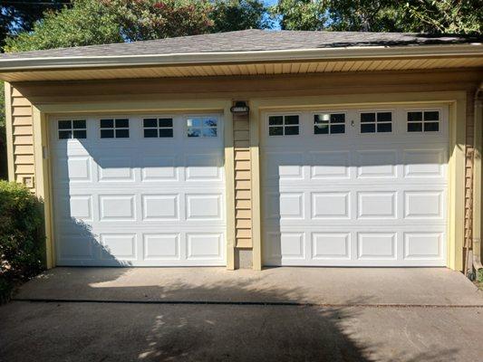 Two single wide garage doors with a full row of glass windows and decorative inserts