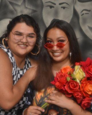 Two people in a photo shot with a Smile Now, Cry Later backdrop.