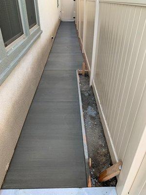 Concrete side yard with wood inserts to close gaps between the fence, and vine planter bed outline