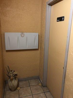 "WTF is a Baby Diaper Changing Station doing OUTSIDE THE RESTROOMS and in the Public View (hallway OUTSIDE both restrooms) ?"