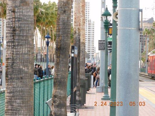 Gaslamp quarter with people running through the trolley station as the trains cross.