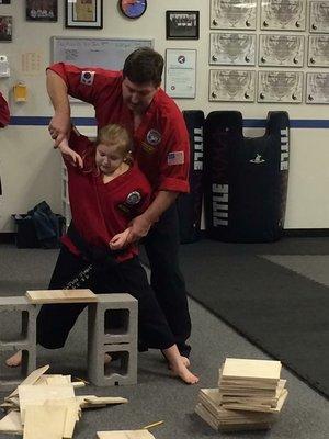 Little Grace getting instruction on palm strike board breaking from Master Jimmy