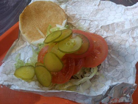 sausage sandwich piled high with extra lettuce, tomatoes and pickles