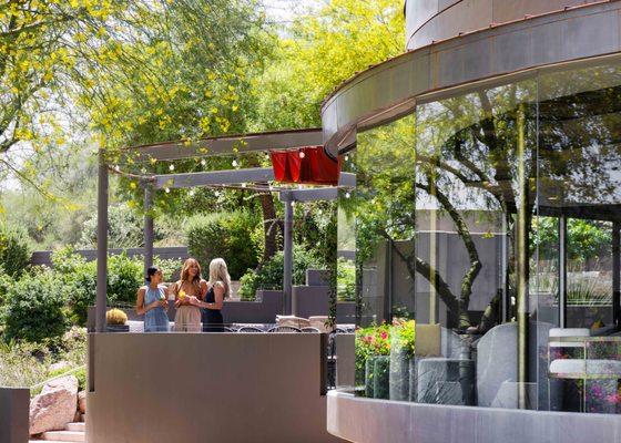 Three women enjoying cocktails on jade bar outdoor patio.