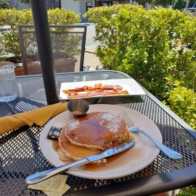 Pancakes and side of bacon on the patio.