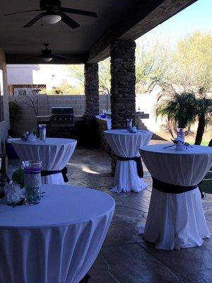 Several hi-top tables with white linen and sashes