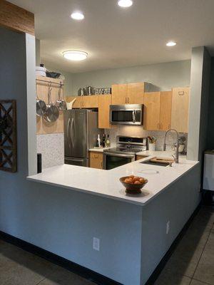 Cut off the higher bar and overhang, quartz countertops, recessed lighting, tile backsplash, and a fancy sink!  Oh. And painted the wall!