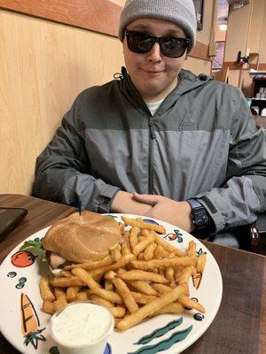 He is acting silly with his great burger in front of him.