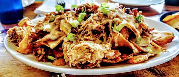 Loaded Cheesy Chips - home cooked potato chips topped with pulled chicken, bacon, melted spicy queso cheese and green onions.