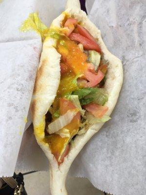 Samoon bread filled with fried eggplant, fries, falafel, tomato, and lettuce topped with amba (slightly spicy mango sauce)