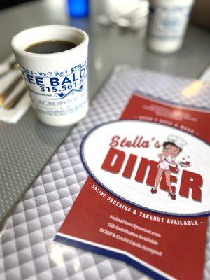 Front of Stella's diner menu with a cup of coffee on the side.