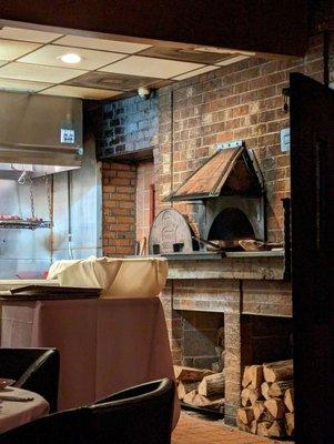 Inside. Brick wood-fired oven with steaks suspended above the grill in the back.