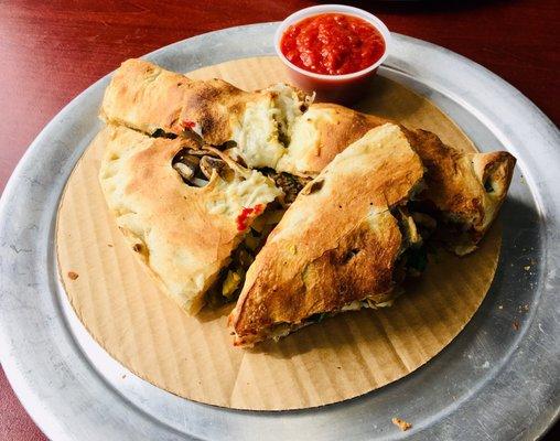 Ridiculously DELICIOUS calzone, with vegan sausage & cheese, mushrooms, spinach, onions, and jalapeños.