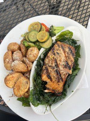 Salmon over flash fried spinach, roasted potatoes and fresh veggies.