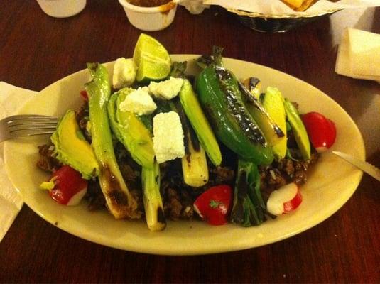 Sergio's Plate. Carne Asada over whole beans with grilled onions and avocado on top.