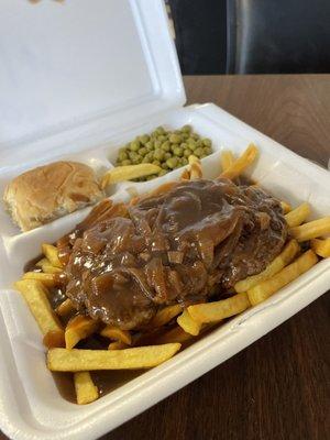 Hamburger steak dinner over fries.