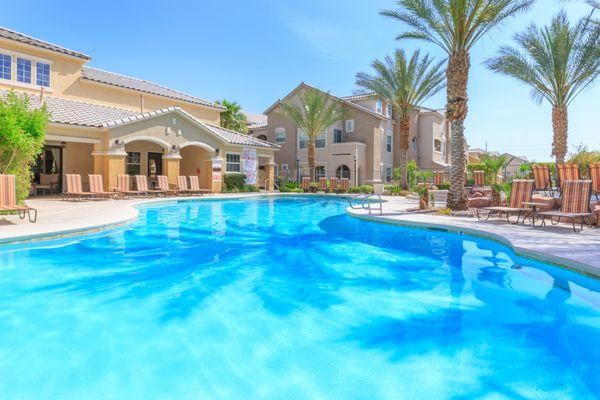 Resort-style pool with palm shadows and view to mission-inspired natural yellow property exterior.