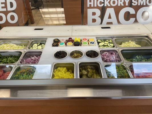 Veggie toppings all fresh, cut nicely, clean workstation and all organized.