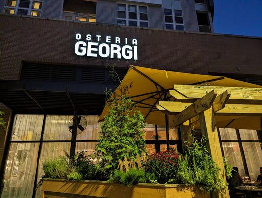 Osteria Georgi signage, outside at night. View facing south, southeast, from Village Plaza side.