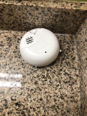 Smoke alarm in puddle of water on the counter.