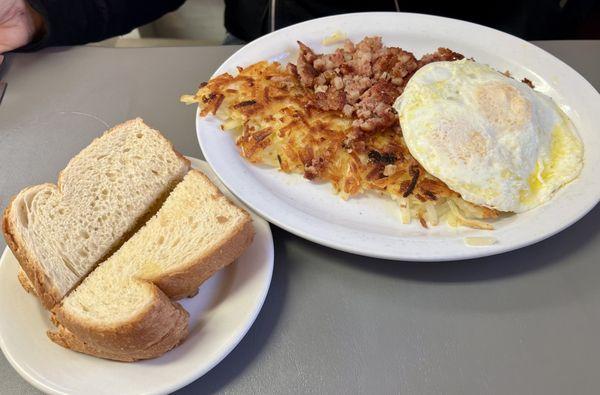 Corned beef and hash with medium eggs, hash browns and side of toast.