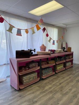 Shelves of bolts of fabric with colorful bunting hanging above.