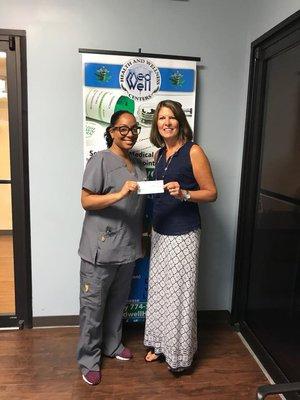 Patient Care Specialist Cassandra present the MedWell Cares donation check to Team Intestinal Fortitude!