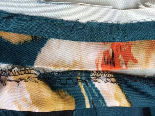 Inside original hem (with teal ribbon): top
 Her hem: bottom, with puckered, uneven stitching.