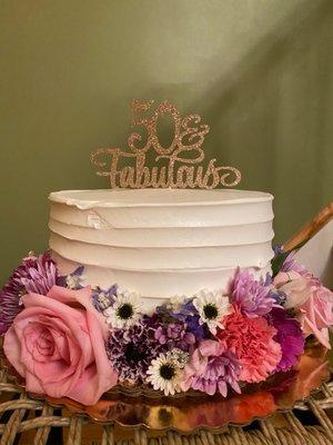 A vanilla cake with lemon mousse, simply decorated with fresh flowers for a 50th birthday.