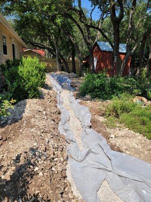 French drain being installed to divert water and alleviate drainage issues