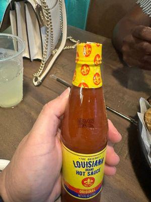 Hot sauce with the wrapper still on the lid.