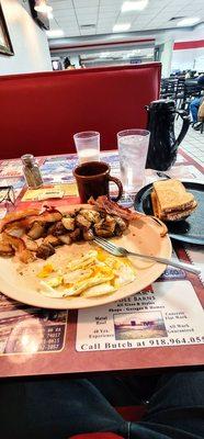 Eggs and meat traditional Over medium home fries seasoned on the grill bacon sourdough toast coffee