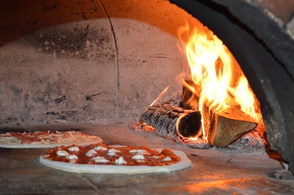 Pizzas cooking by the fire.