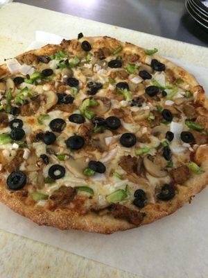 A specialty pizza with olives, musrooms, onions, and green peppers.