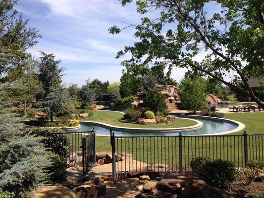 Lazy river connecting to a pool with surrounding landscape designed by Scapes, inc.