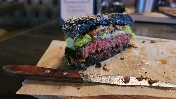 The Wagyu Burger topped w/white cheddar, caramelized onions & tomato jam(lettuce), w/apple slaw on black focaccia