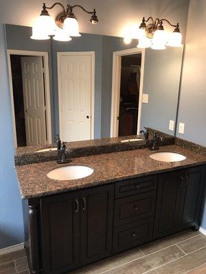 Cabinet and granite installed with a new mirror and flooring