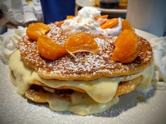 Orange pancakes with an orange cream filling, tangerine slices, orange candy, and whip cream.