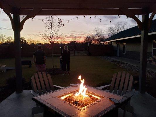 Nice fire pit outside by the game area that has cornhole.