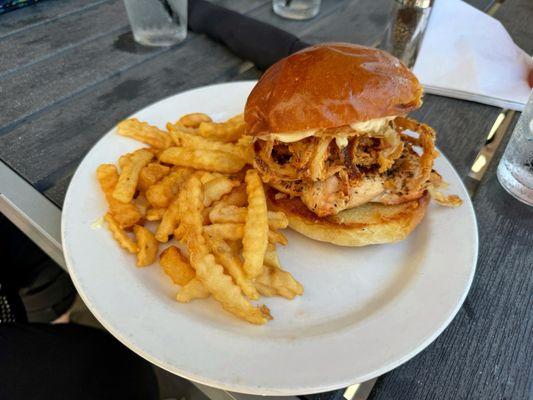 Blackened Chicken on Brioche with fried onion strings and a side of fries.