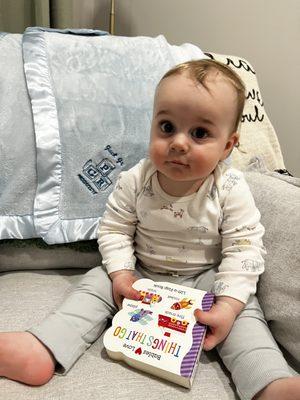 Baby Jack reading "Things that go" and showing off his progressive insurance blanket