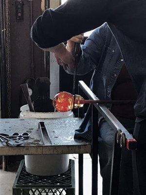 Instructor helping one of the class participants use a Jack to shape a glass form.