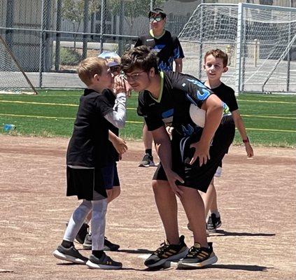 Campers "strategizing" with our coach to win the kickball game. Outdoor games all summer long