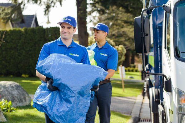 1-800-GOT-JUNK? Truck Team Members carrying trash bags