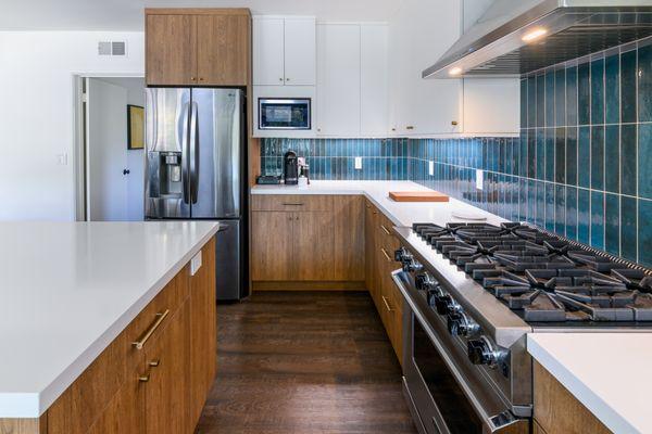 Woodland Hills Mid Century Modern kitchen.    Slab laminate doors paired with white upper cabinets and a teal color back splash tile.