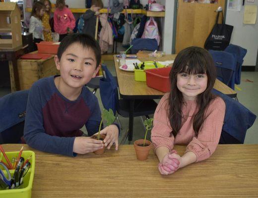 A boy and girl with potted plants.