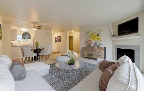 Staged living and dining room with a fireplace and access to a kitchen.