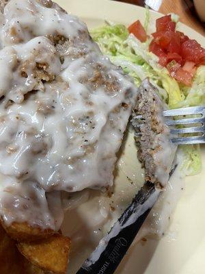 Chicken fried steak is a thick, tender cutlet enveloped in a light, crispy batter that holds together well as you carve into it.